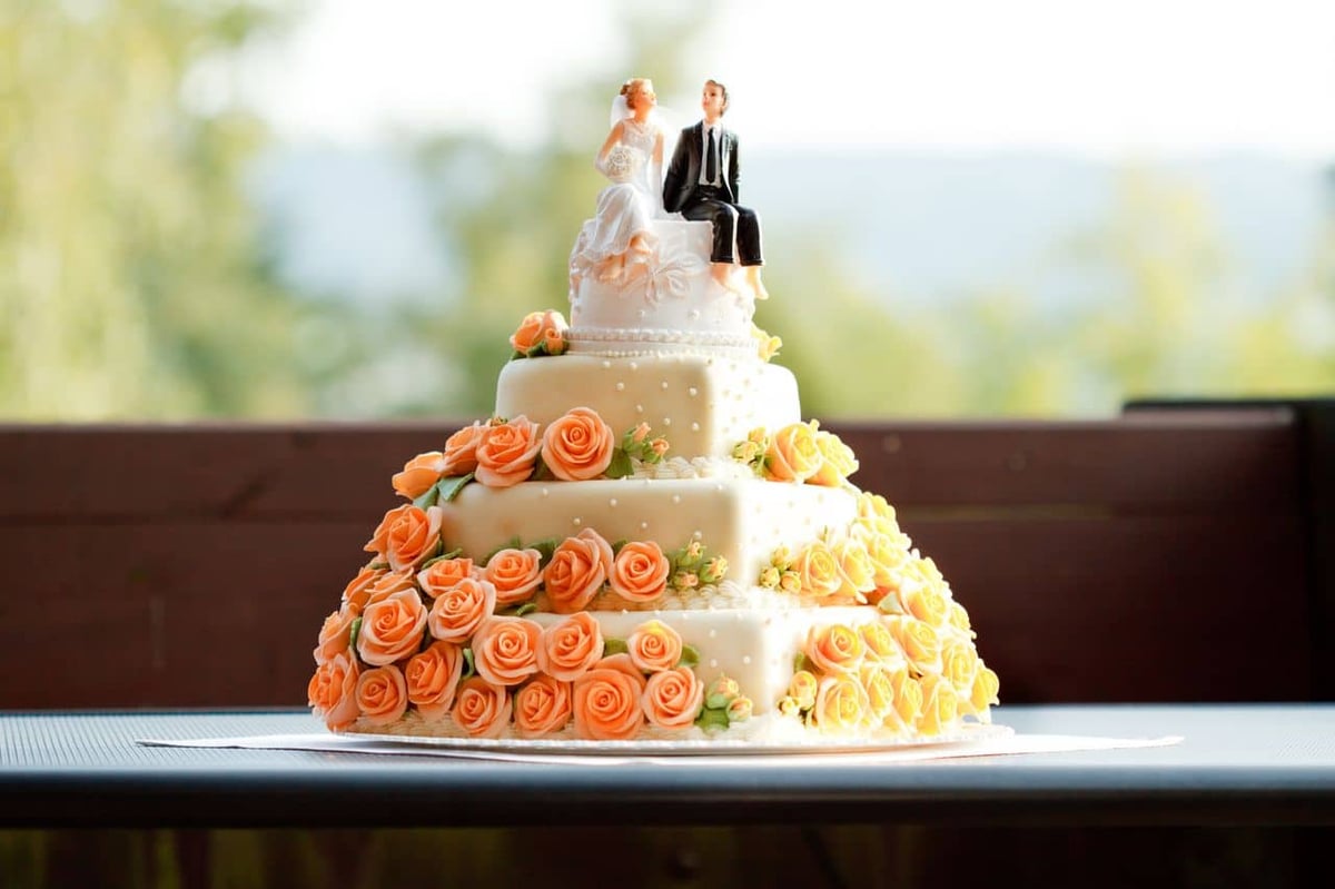 Hochzeitstorte mit Brautpaar mit Rosen