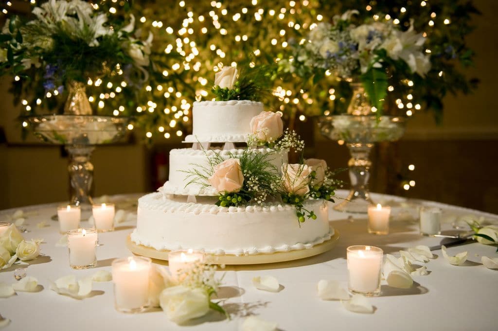 Hochzeitstorte auf Tisch dekoriert mit Windlichtern